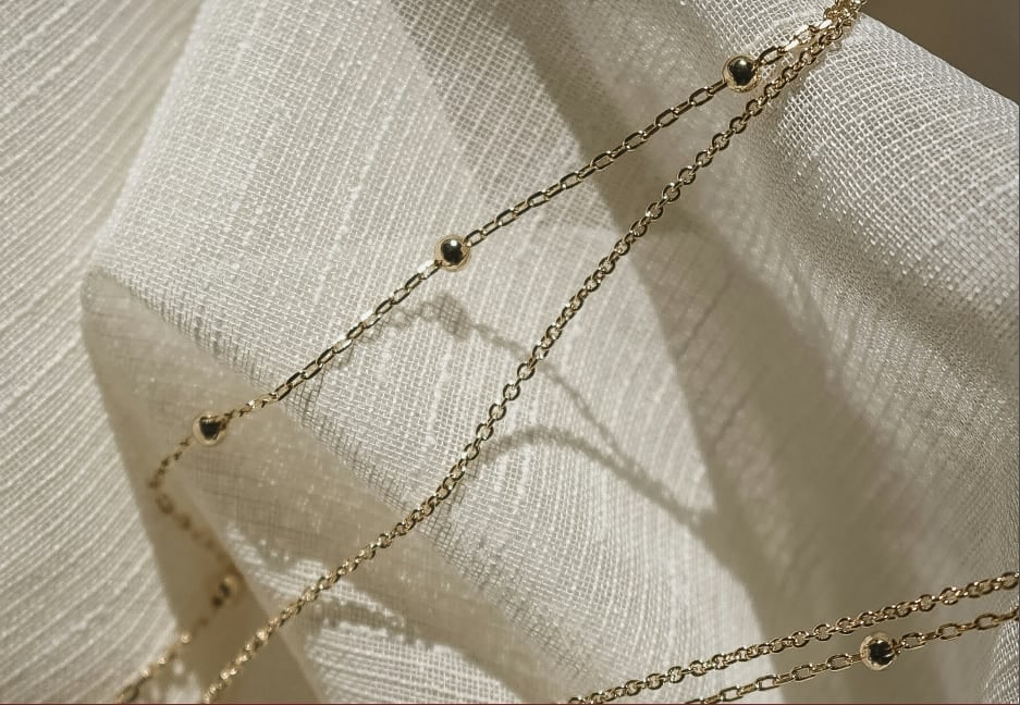 Finished necklace draped across cream linen