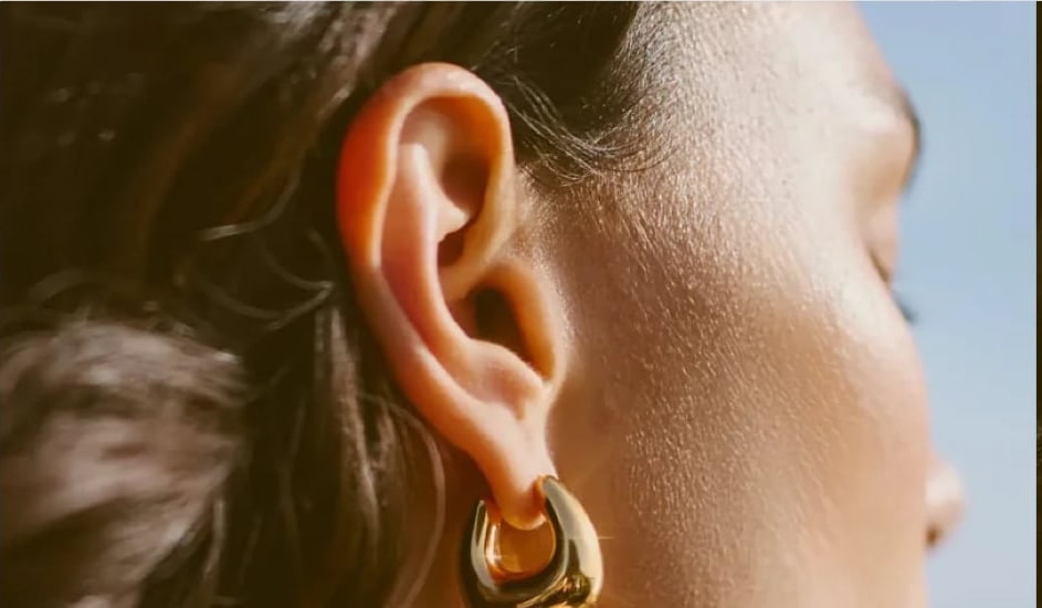 Gold hoop earring on a model in golden-hour light