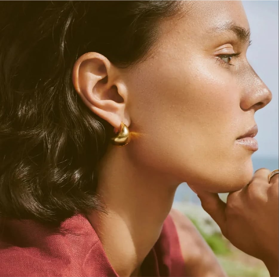 Gold hoop earring on a model in soft window light