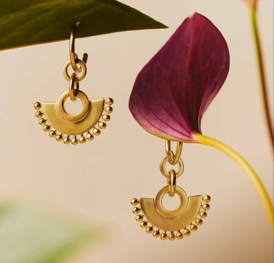 Fan chandelier hoop earrings against a green leaf and burgundy flower