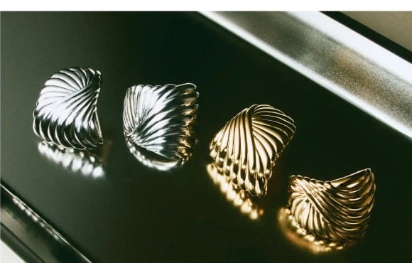Four shell-shaped earrings on a polished surface